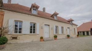a white house with white shutters and a driveway at Le cottage in Payns