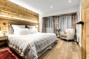 a bedroom with a large bed and a chair at Hôtel La Sivolière in Courchevel