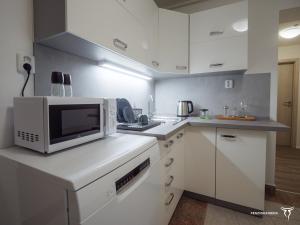 a kitchen with white cabinets and a microwave at Penzion Korida in Ústí nad Labem