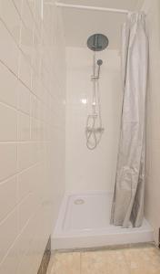 La salle de bains blanche est pourvue d'une douche avec rideau de douche. dans l'établissement L'esperance, à Ferreux