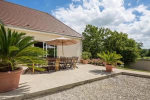 a patio with an umbrella and chairs and plants at La goutte d'or in Baroville