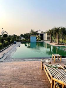 a large swimming pool with a wooden bench in front of it at The River Side Resort & Farm in Noida