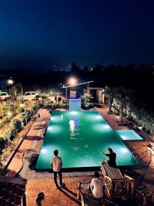 two people standing around a large pool at night at The River Side Resort & Farm in Noida