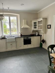 una cocina con armarios blancos y fregadero en Kuflew Manor House, en Mrozy