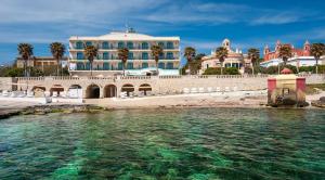 a large building on a beach with the water at HOTIDAY Leuca Lungomare in Leuca