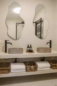 two mirrors above two sinks on a shelf with baskets at Luxe appartement in Antwerpen in Antwerp