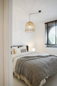 a white bedroom with a bed and a chandelier at Luxe appartement in Antwerpen in Antwerp