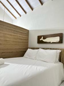 um quarto com 2 camas brancas e uma cabeceira em madeira em Chalé da Mata Trancoso em Trancoso