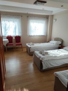 オストルフ・ビエルコポルスキにあるBankietowa Hotel & Restauracjaのベッド3台と赤い椅子2脚が備わる部屋