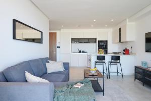 a living room with a blue couch and a kitchen at Apartment Sea View B2 - Mosquée Hassan II - By TheCasaEdition in Casablanca