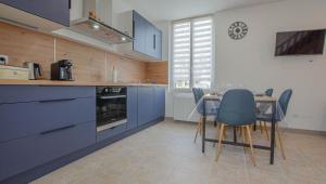 a kitchen with blue cabinets and a table and chairs at Le paco in Bar-sur-Aube +7 photos
