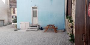 niebieski budynek z drewnianą ławką obok stołu w obiekcie Le paco w mieście Bar-sur-Aube