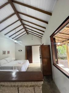 um quarto com uma cama e uma grande janela em Chalé da Mata Trancoso em Trancoso