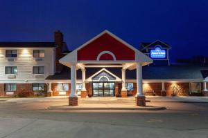 a hotel with a red and white building at night at AmericInn by Wyndham Peoria in Peoria