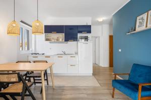 a kitchen and dining room with a table and a blue chair at Regina Apartments in Brodarica