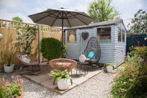 een patio in de achtertuin met stoelen en een parasol bij Whitstable Cottage - Perfect Location in Whitstable