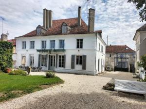 una gran casa blanca con un banco delante en Demeures des grands lacs de champagne, en Brienne-le-Château