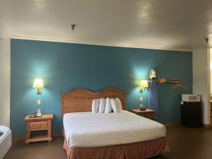 a bedroom with a bed and a blue wall at Motel 6 Portland, IN in Portland