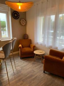 a living room with two chairs and a table and windows at Villa des Pins in Jullouville-les-Pins +29 photos