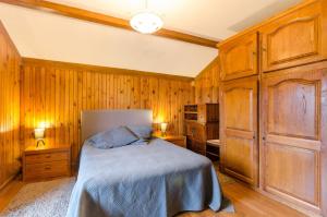 a bedroom with wooden walls and a bed with blue sheets at La sablonniere in La Ville-aux-Bois