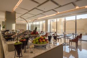 ein Restaurant mit Tischen, Stühlen und Obst auf der Theke in der Unterkunft Enala Hotel- Umluj in Umm Lajj