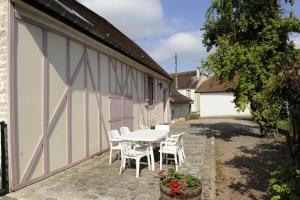 a patio with a table and chairs next to a building at La compagnie du soleil in Bligny