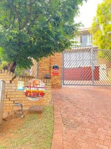 un muro di mattoni con un cartello accanto a una recinzione di C and C GUEST HOUSE/ BED AND BREAKFAST a Pretoria