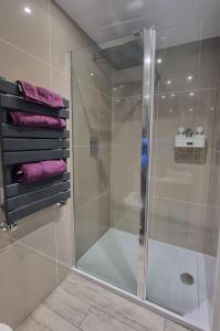 y baño con ducha de cristal y toallas púrpuras. en Studio 5 en Woolacombe