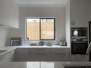 オークランドにあるMurphys Guest Homeの白いカウンターと窓付きのキッチン