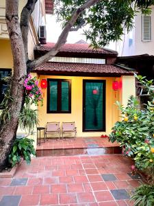 een geel huis met 2 stoelen op een bakstenen patio bij Lee Homestay in Hanoi