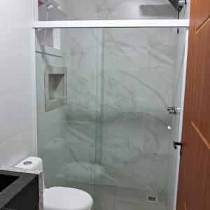a bathroom with a glass shower with a toilet at Pousada Tia Alice in Penha