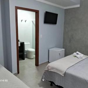a room with two beds and a bathroom with a toilet at Pousada Tia Alice in Penha