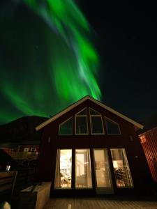 une maison avec des lumières vertes du nord dans le ciel dans l'établissement Rorbu Skreda, à Leknes