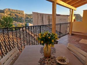 una mesa con un jarrón de flores en el balcón en B&B Chiaro di Luna en Corleone