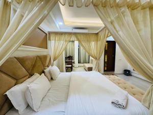 um quarto com uma grande cama branca com cortinas em Hotel Shree Palace em Ujaim