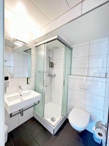 a bathroom with a shower and a toilet and a sink at Hotel Royal Luzern in Luzern