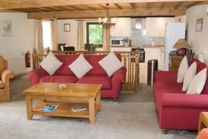 a living room with two red couches and a table at Saddleback Barn in Penrith