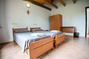 LàconiにあるOASI FRANCESCANA SANT'IGNAZIO DA LACONIのベッド2台(壁にクロス付)が備わるベッドルーム1室