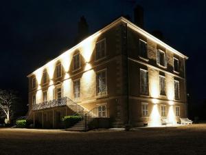 Un gran edificio con luces por la noche. en Le chateau de crespy, en Crespy-le-Neuf