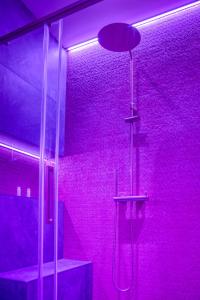 La salle de bains est pourvue d'une douche avec un éclairage violet. dans l'établissement Le Mille et une nuit - Love Room - Championnet, à Grenoble