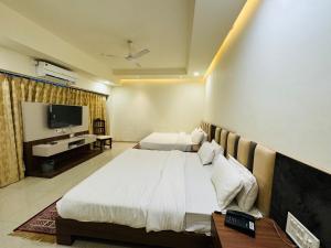um quarto de hotel com uma cama e uma televisão em Hotel Shree Palace em Ujaim