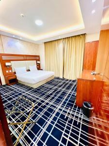 a hotel room with a bed and a room with blue floors at Shatha Abha Furnished Units in Abha