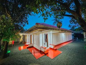 a small white building with a tree in the foreground at Villa Beach Heaven in Hikkaduwa