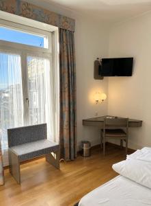 um quarto de hotel com uma secretária e uma janela em Hotel Royal Luzern em Lucerna