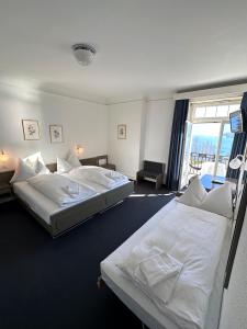 two beds in a room with a large window at Hotel Royal Luzern in Luzern