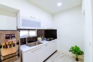 a kitchen with white cabinets and a stainless steel refrigerator at Itaewon in Tainan