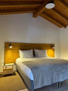 a bedroom with a large bed with a wooden headboard at Quinta da Boavista in Vila Nova de Milfontes