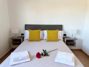 a bed with two pillows and a rose on it at Cómoda villa en la montaña in Gran Tarajal