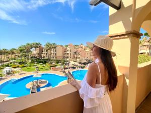 a woman standing on a balcony looking out at a pool at Wyndham Grand Costa del Sol in Mijas Costa