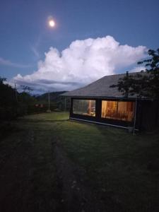 een huis met een zwart dak met de maan in de lucht bij Chalé Araucária- Vale das Pedras MG in Sapucaí-Mirim